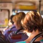 image is of the back of a womans head seated on a bus