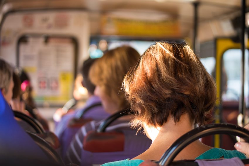 image is of the back of a womans head seated on a bus